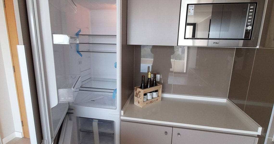 Cocina americana equipada con encimera y horno empotrado en departamento 1D/1B.