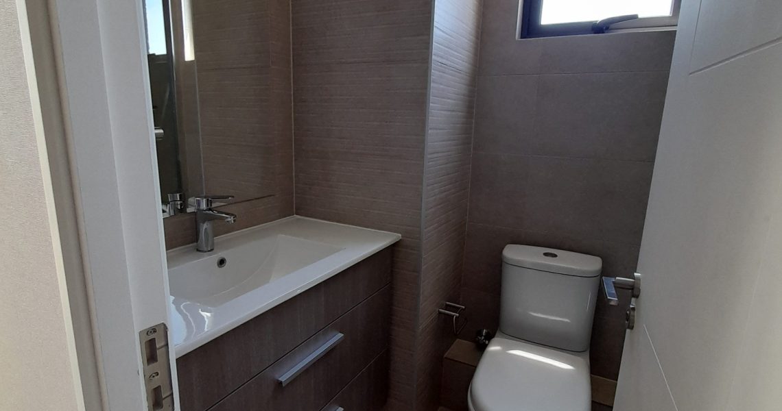 Baño moderno con shower door y vanitorio en departamento en La Reina.