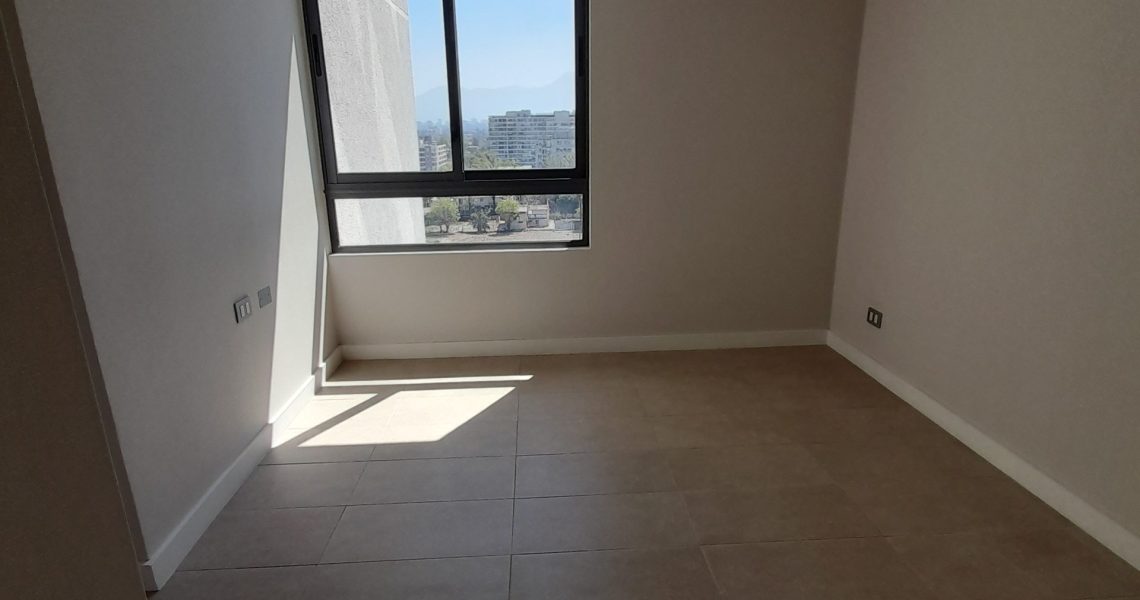 Dormitorio principal con clóset y luz natural en departamento en La Reina.